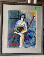 Photo of framed abstract painting featuring a seated nude figure in abstract style with blues, reds, and other colors.