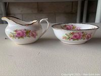 Side profile of cream and sugar set showing floral pattern and gold trim on bone china.