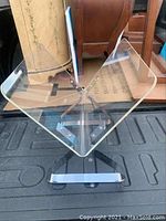 Clear angled acrylic and chrome magazine stand viewed from the top, showing the V-shaped clear acrylic top and sides with chrome support legs.