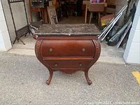 Front view of a wooden drawer stand with a polished marble top and two drawers with decorative knobs.