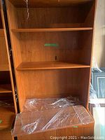 Full view of teak wood unit showing three open shelves and protective wrapping on surfaces