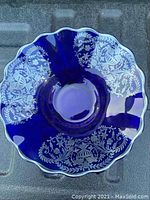 Top view of the cobalt blue glass bowl showing intricate silver overlay floral and leafy patterns along the scalloped edge.