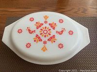 Top view of white lid with red and orange floral and bird pattern