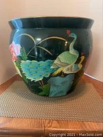 Front side showing two peacocks and floral design on dark green ceramic pot.