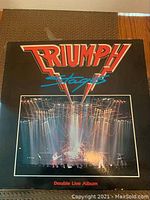 Front cover of Triumph 'Stages' double live album vinyl showing band performance photo and logo.