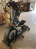 Front/side view of full elliptical machine showing overall structure, console, and foot pedals
