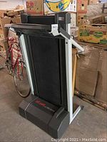 Front view of the folded folded Weslo Sport 350 treadmill surrounded by boxes and storage items.