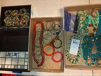 Photo showing an assortment of colorful costume bracelets and a jewelry box with a tile-patterned lid interior