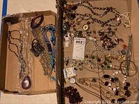 First photo showing multiple costume jewelry pieces including beaded necklaces, bracelets, and earrings arranged in an open box.