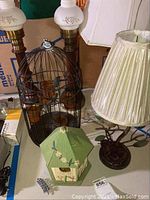 Birdcage with birds and candleholders, matching desk lamps, and decorative birdhouse visible on table
