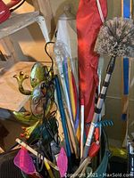 Photo of yard decor metal frog, long handled brush, umbrellas including Tommy Bahama bag and multicolor umbrellas