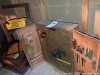 Photo showing the opened vintage wooden chest containing the hand drill, handsaw, screwdrivers, pliers, and other tools.