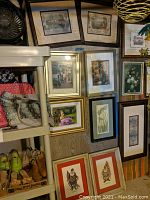 Photo showing a group of framed wall art prints hung on a wall including floral and scenic subjects in various wood and gold frames.