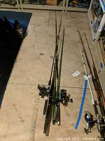 Photo of eight fishing poles and attached reels laid out on a floor showing various brands and models.