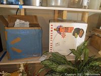 View of the Tayama soymilk maker box and the George Foreman grill box on a shelf.