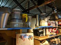 Shelf with various kitchen appliances and containers including Back to Basics blender, Brita pitcher, Sensation carafes, Firewall electric pitcher, and food containers.