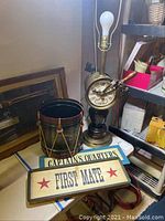 Photo showing the metal nautical lamp, replica metal drum, and two wooden nautical plaques.