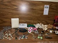 Wide shot showing assorted costume jewelry including beaded necklaces, rings, bracelets, and wristwatches arranged on a wooden surface