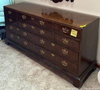 Front angle view of the Henredon dresser showing all 10 drawers and brass pull hardware, highlighting the polished wood surface and light scratch wear.