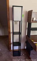 Full view of the black floor lamp with three shelves and rectangular lamp frame at top, showing lamp structure and condition.