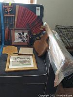 Overview of the shelf, fan, wind chime, framed pictures, leaves vase holder and wooden paddle on a chair and floor.