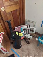 Overview of the lot contents showing photo albums, picture frames, and the black Air Innovation humidifier on the floor by a door