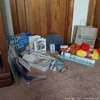 Full view of lot showing yarn skeins, craft books, templates, tools, and greeting cards arranged against wood paneling.