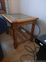 Side view of rectangular wood framed side table with turned legs and lower slatted shelf, showing glass top and crack.
