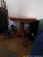 Side view of round wooden table showing pedestal and claw foot design