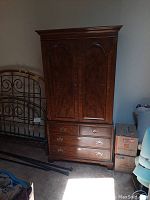 Front view of Henredon armoire showing two paneled upper doors, four drawers below with brass pulls, wood finish with some scratches visible.