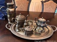 Full view of the tea set arranged on an ornate silver plate serving tray on a dining table, showing all pieces together including the pewter shaker and the silver plate tea set components.