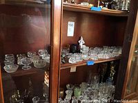 Several shelves showing glass salt dips arranged in rows, mostly clear with different patterns and shapes.