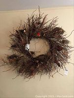 Front view of large wreath made of twigs with birds' nests and small bird decorations, hung on wall.
