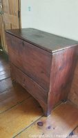 Photo of antique wooden blanket chest showing front and left side with visible wear on wood surface