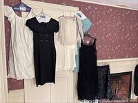 Full view of 7 vintage women's dresses and dresswear hanging on a rack, showing variety in color and style