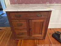 Front view of the vintage solid wood commode showing three drawers on the left and one cabinet door on the right, with metal handles on drawers and wooden knob on cabinet.