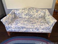 Full front view of blue and white toile camelback loveseat upholstery, showing overall structure and condition.
