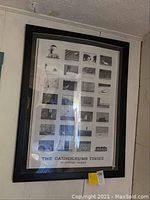 Full view of the framed Edward Gorey poster titled 'The Gashlycrumb Tinies' showing the entire poster in the black plastic frame with visible plexiglass covering and some reflection.