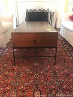 Front view of coffee table showing wood top, metal base, and two side drawers with round handles.