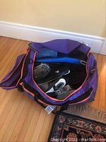 Open duffel bag with visible swim fins and swim shoes inside