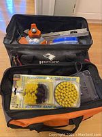 Two Husky tool bags filled with various tools and accessories including a level and orange-handled tools.