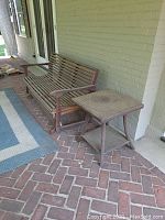 Wooden glider bench and woven rattan side table on brick porch