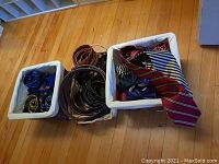 Overview of wicker baskets containing assorted ties and belts, showcasing variety of colors and patterns including striped and solid ties alongside leather belts.