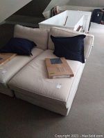 Cream cushioned lounge chair with new fitted slip cover, accompanied by two navy blue pillows and a large pillow on carpeted floor.