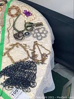 Overview of all jewelry on display including the beaded cap and necklaces on a white cloth.