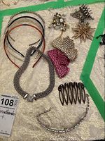 Photo showing assorted hair jewellery including tiara, headbands, clips, star pin, necklaces arranged on cloth background.
