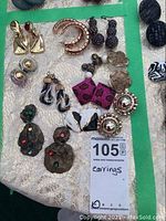 Photo showing eleven pairs of earrings on fabric with mix of pierced and clip styles and a lot sticker.
