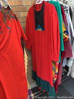 Red robe with colorful block design and green ruffle bottom, displayed on hanger