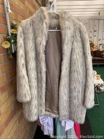 Front view of one faux fur coat showing soft plush fur and smooth brown lining