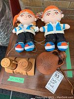 Two Yappie dolls, wooden salt and pepper shakers on tray, and a ceramic flask on a wooden surface.